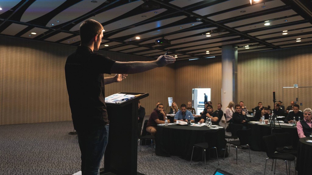 Cameron presenting on stage to a room of builders